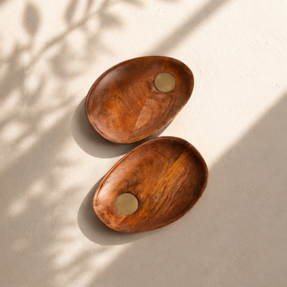 Two wooden trays with metallic centers on a beige surface with shadow patterns.