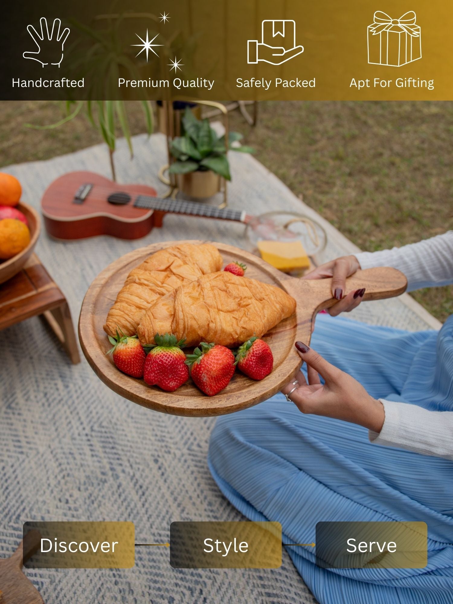 Person holding a wooden plate with a pastry and strawberries in an outdoor setting.