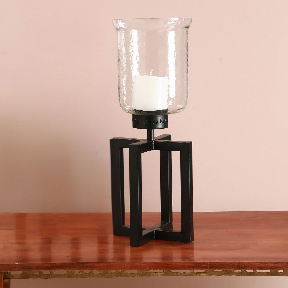 Decorative candle holder with a white candle on a wooden surface against a beige wall.