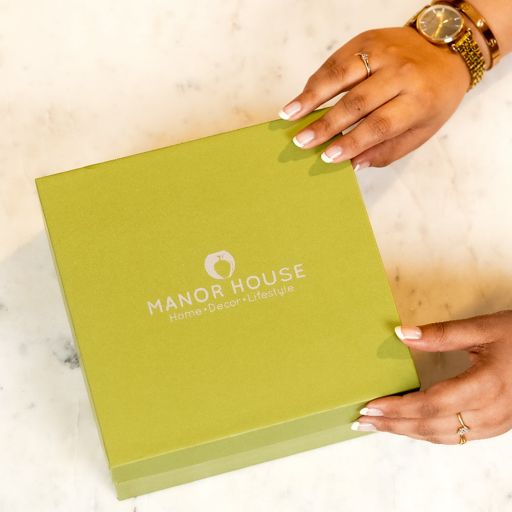 Green box with 'Manor House' logo held by a hand on a light background