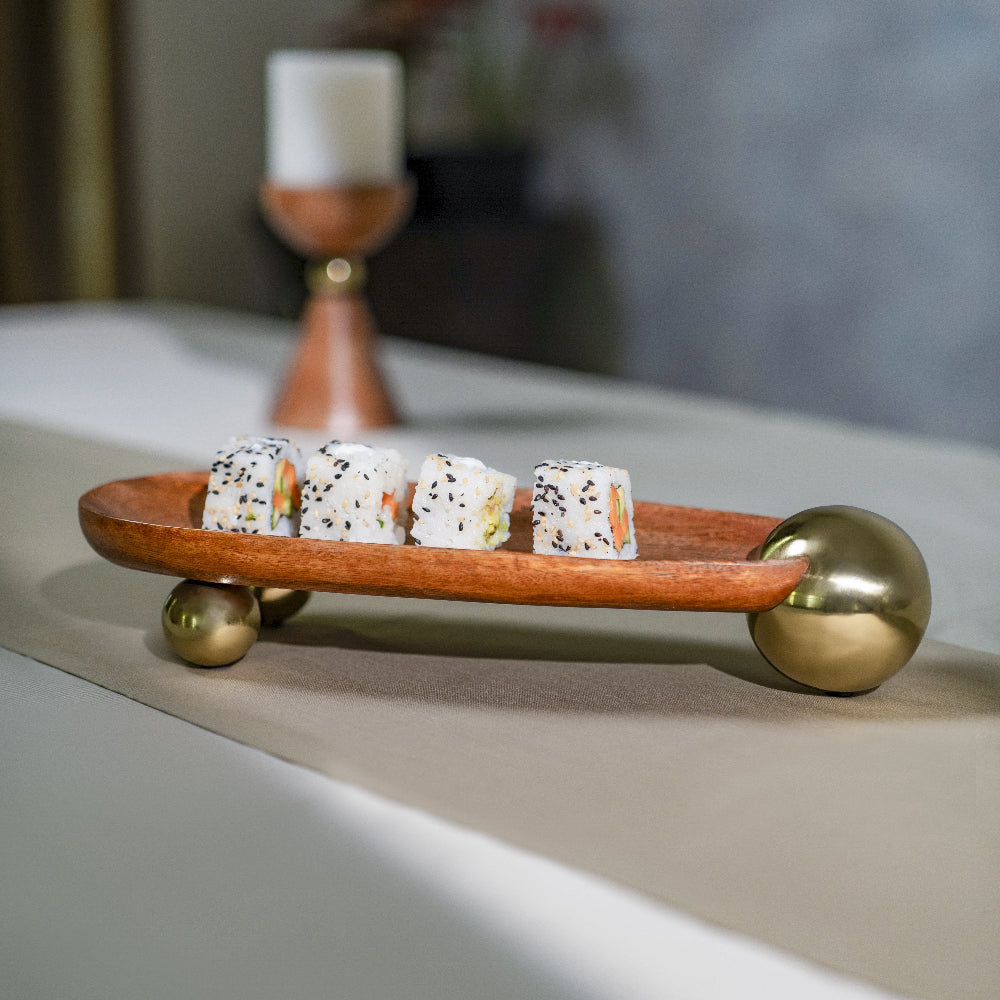 Wooden tray with gold accents holding sushi on a neutral background