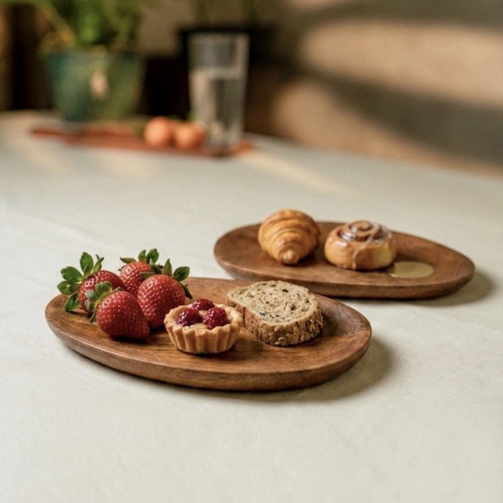 Wooden plates with strawberries, pastries, and bread on a light surface.