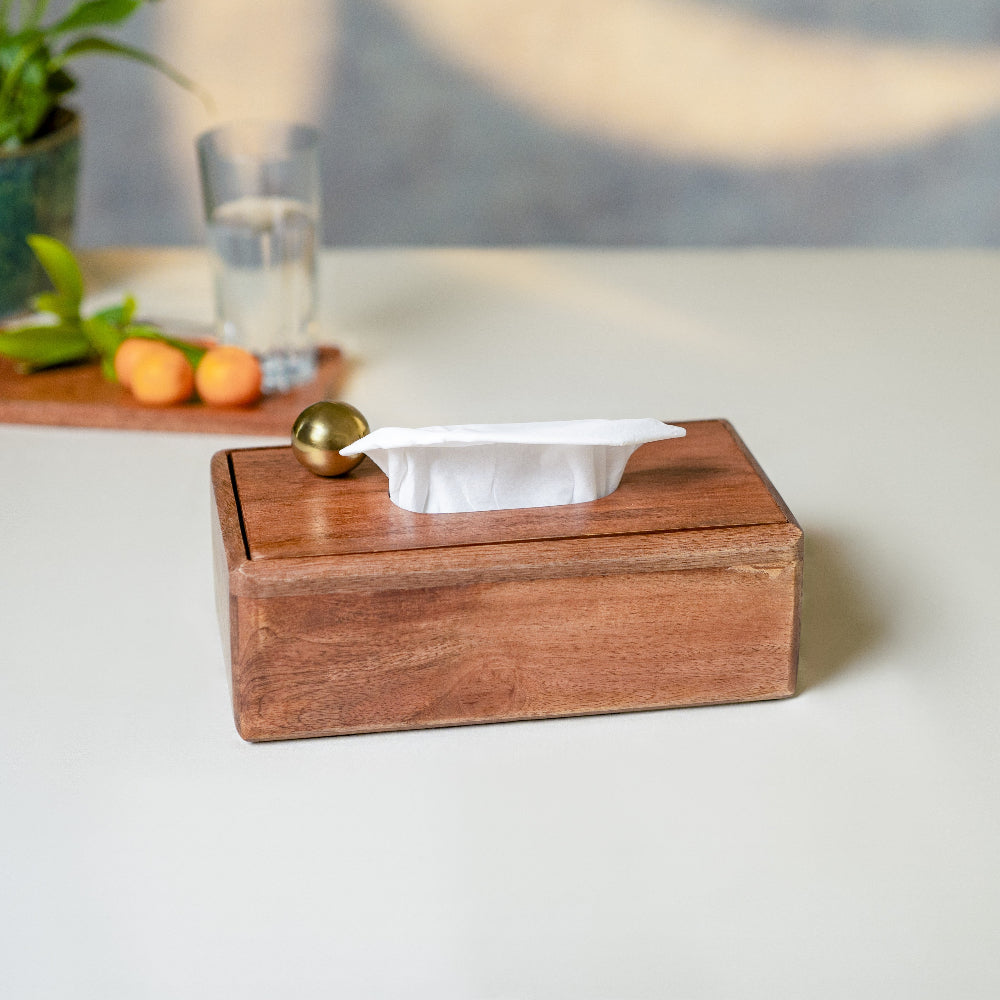 Wooden tissue box with a gold ball on a white surface