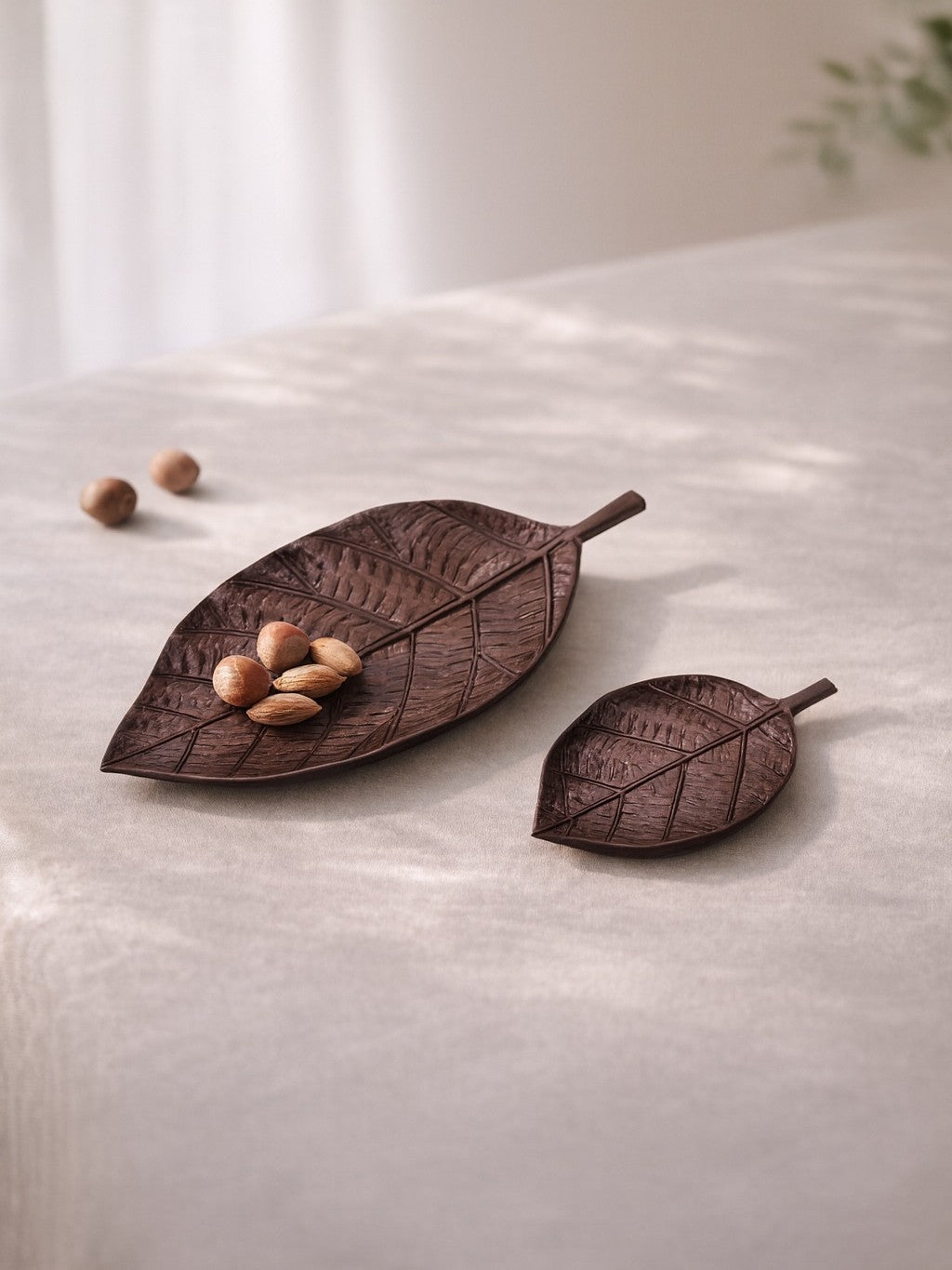 Two leaf-shaped decorative items on a light surface with a blurred background