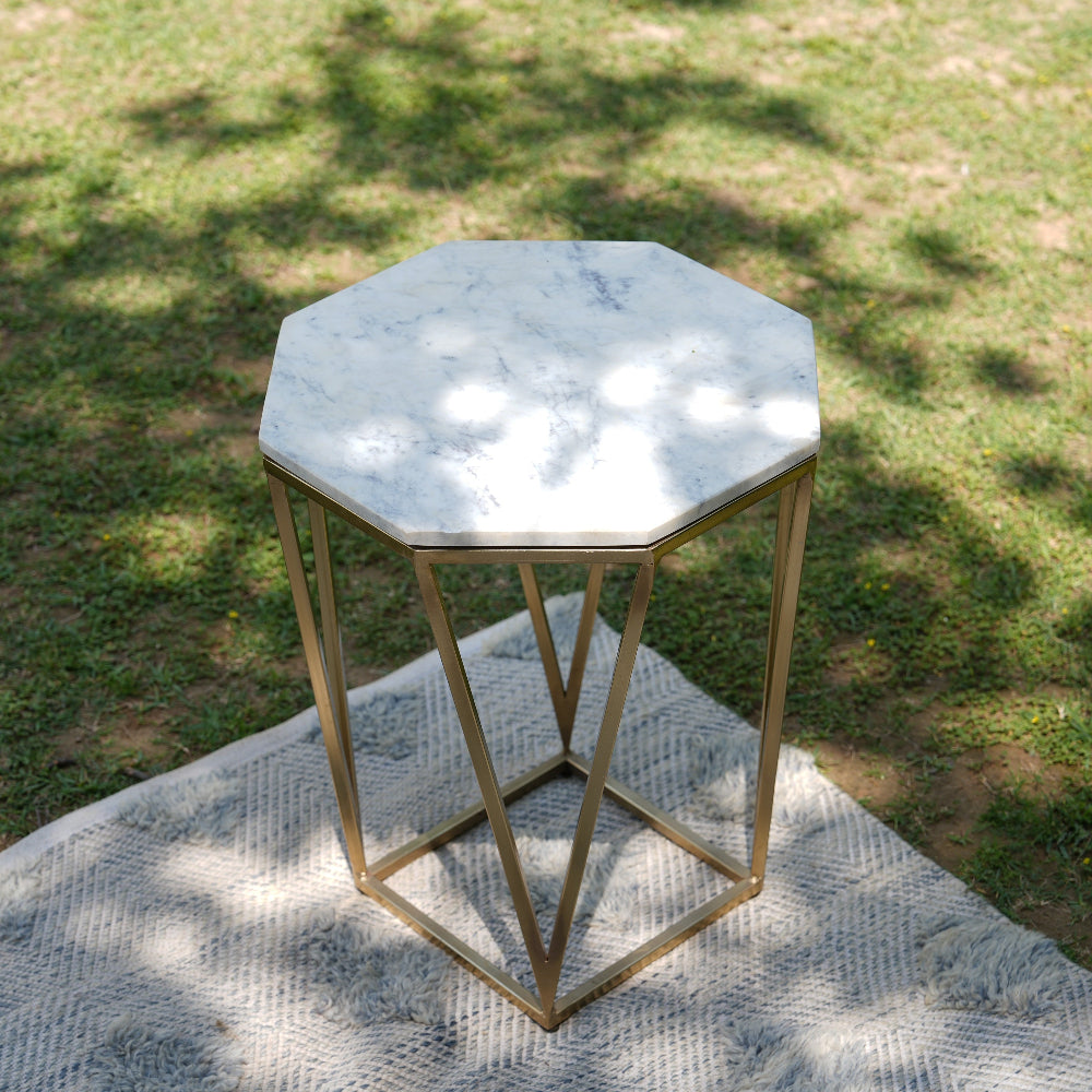 Hexagonal marble table with gold frame on a textured surface outdoors
