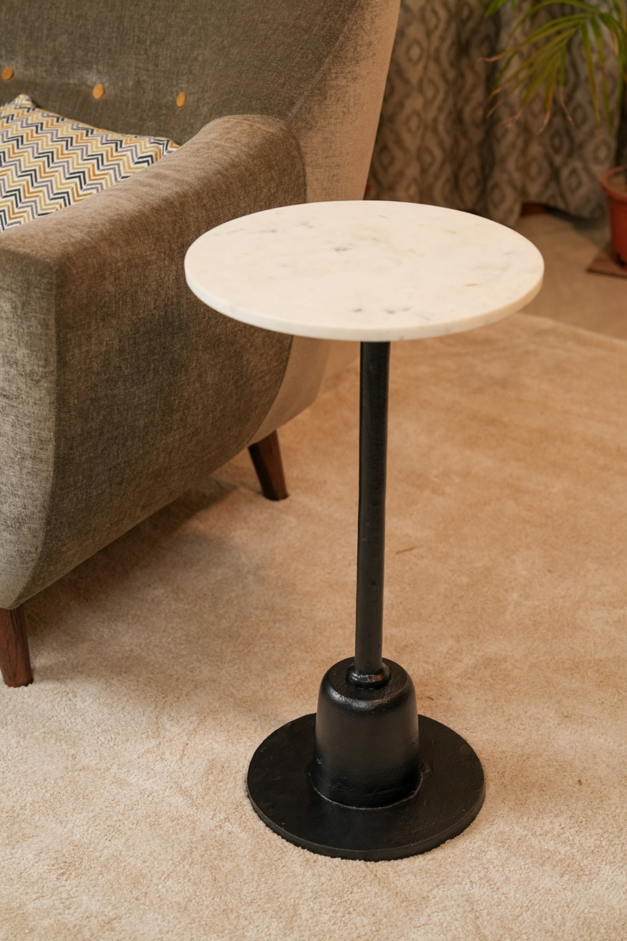 Small round table with marble top and black metal base in a living room setting.