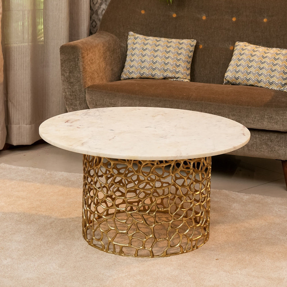 Round marble coffee table with gold lattice base in a living room setting