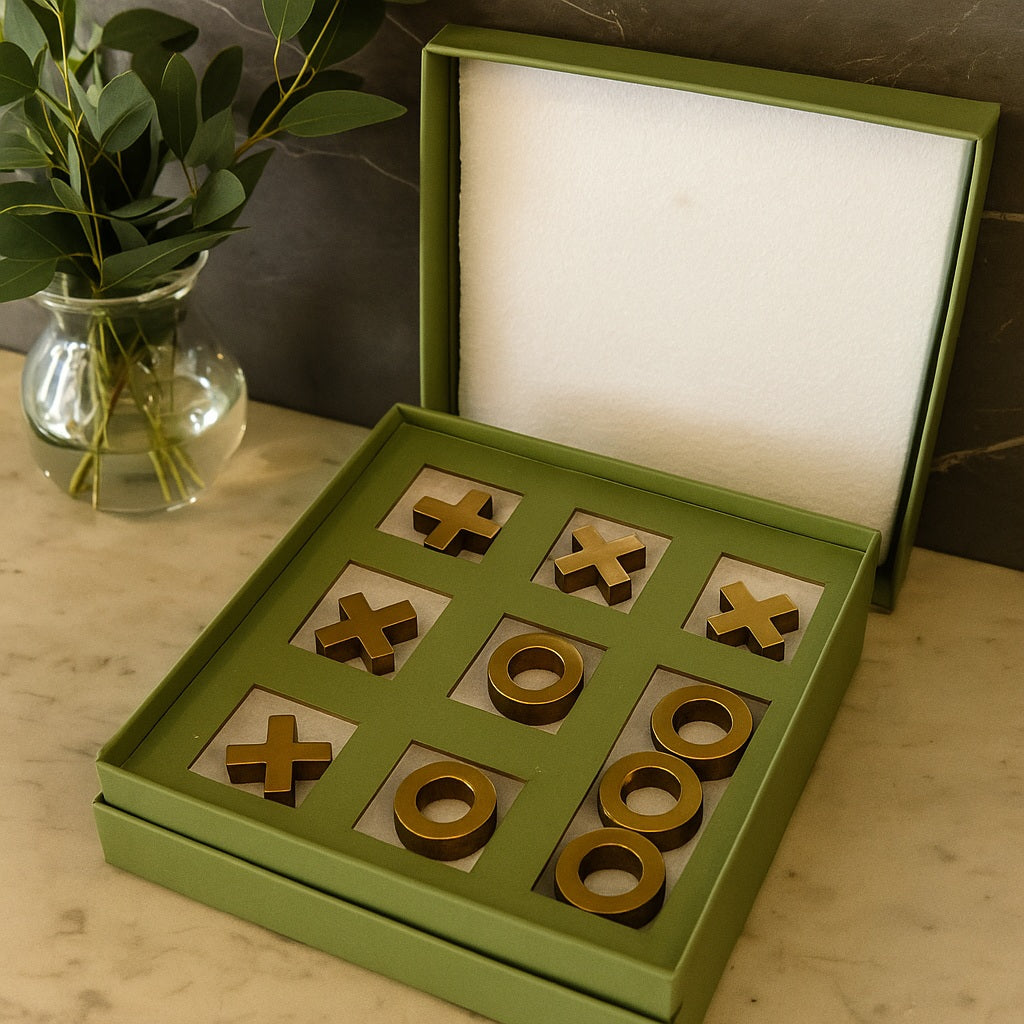Green tic-tac-toe game set on a wooden surface with a vase of plants in the background.