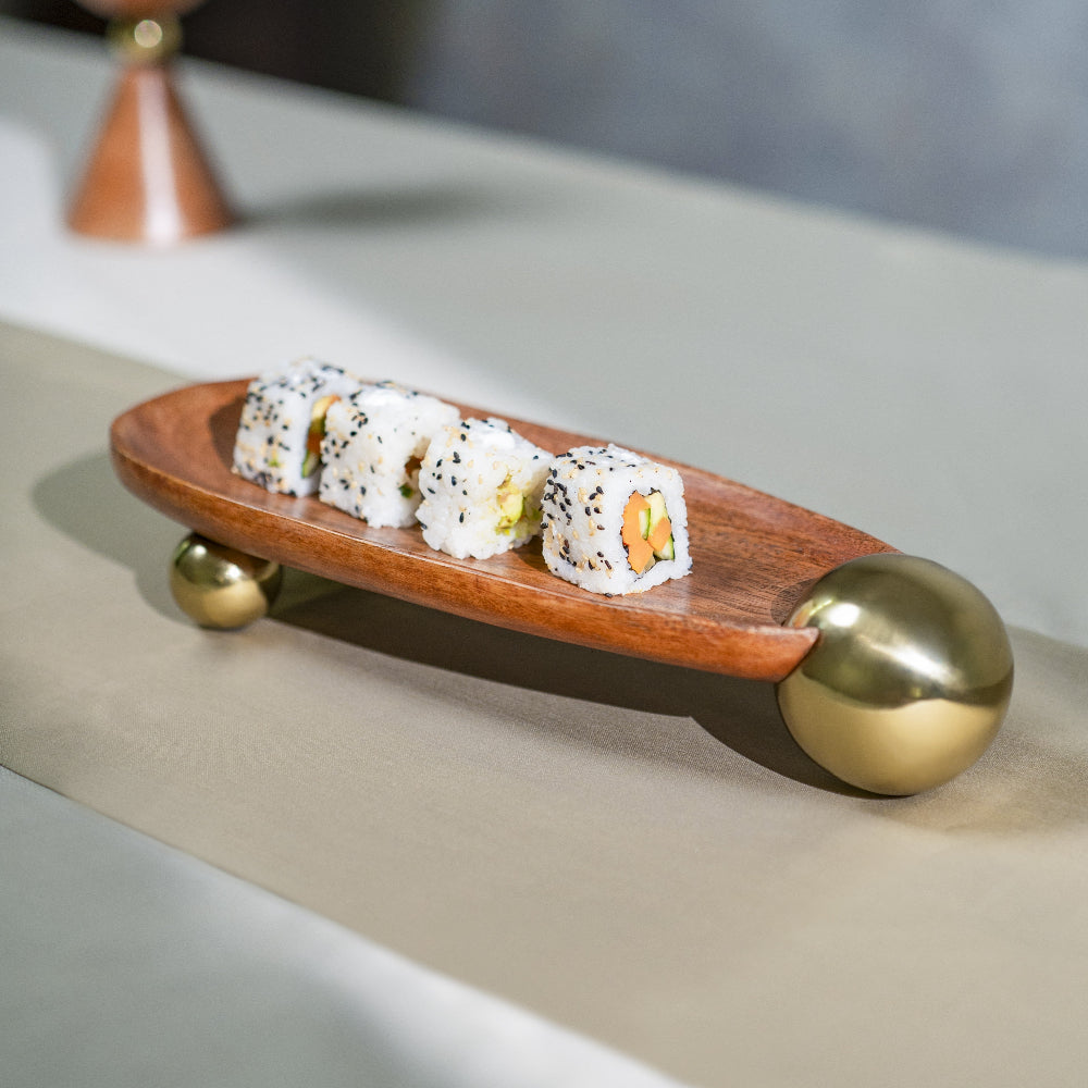 Wooden sushi platter with gold accents holding sushi rolls on a neutral background