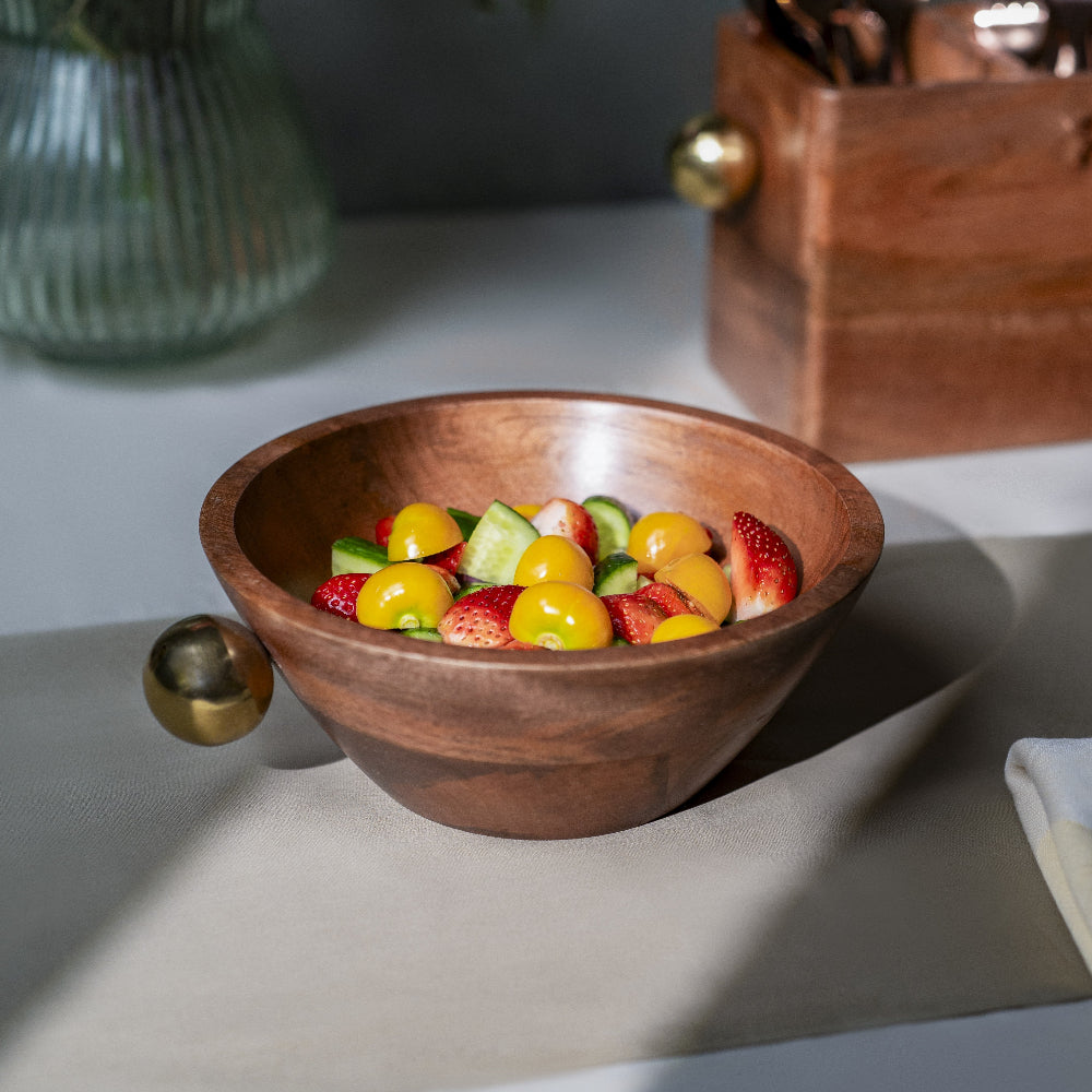 Wooden bowl with fruit salad on a light surface with decorative elements.